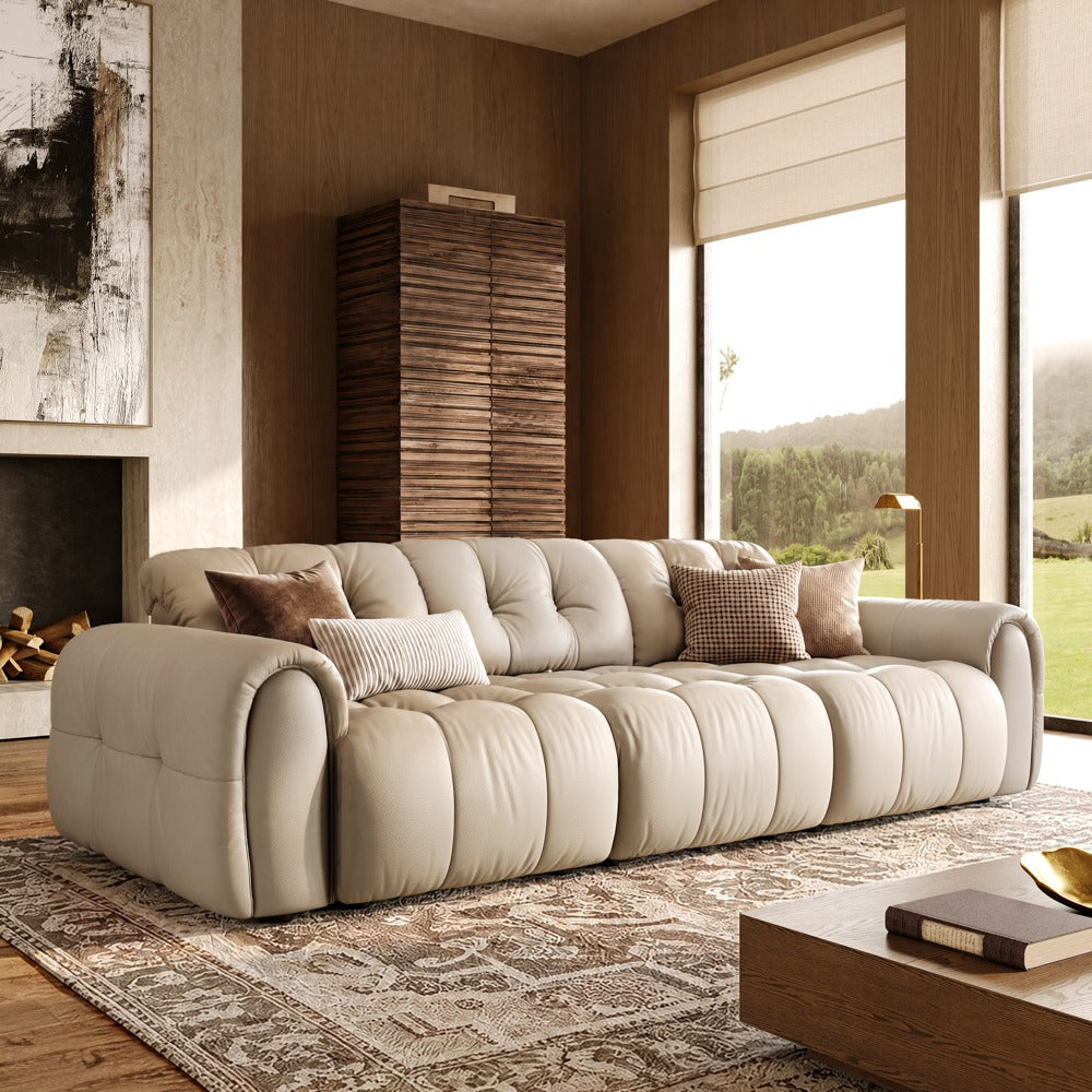 Beige leather tufted modular sofa with three armless seats and two armrests, front view in a living room