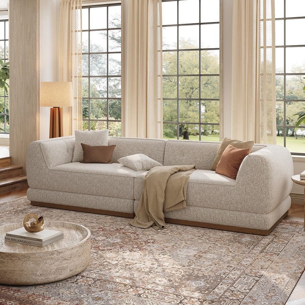 Light gray chenille sofa with wooden base in a bright living room